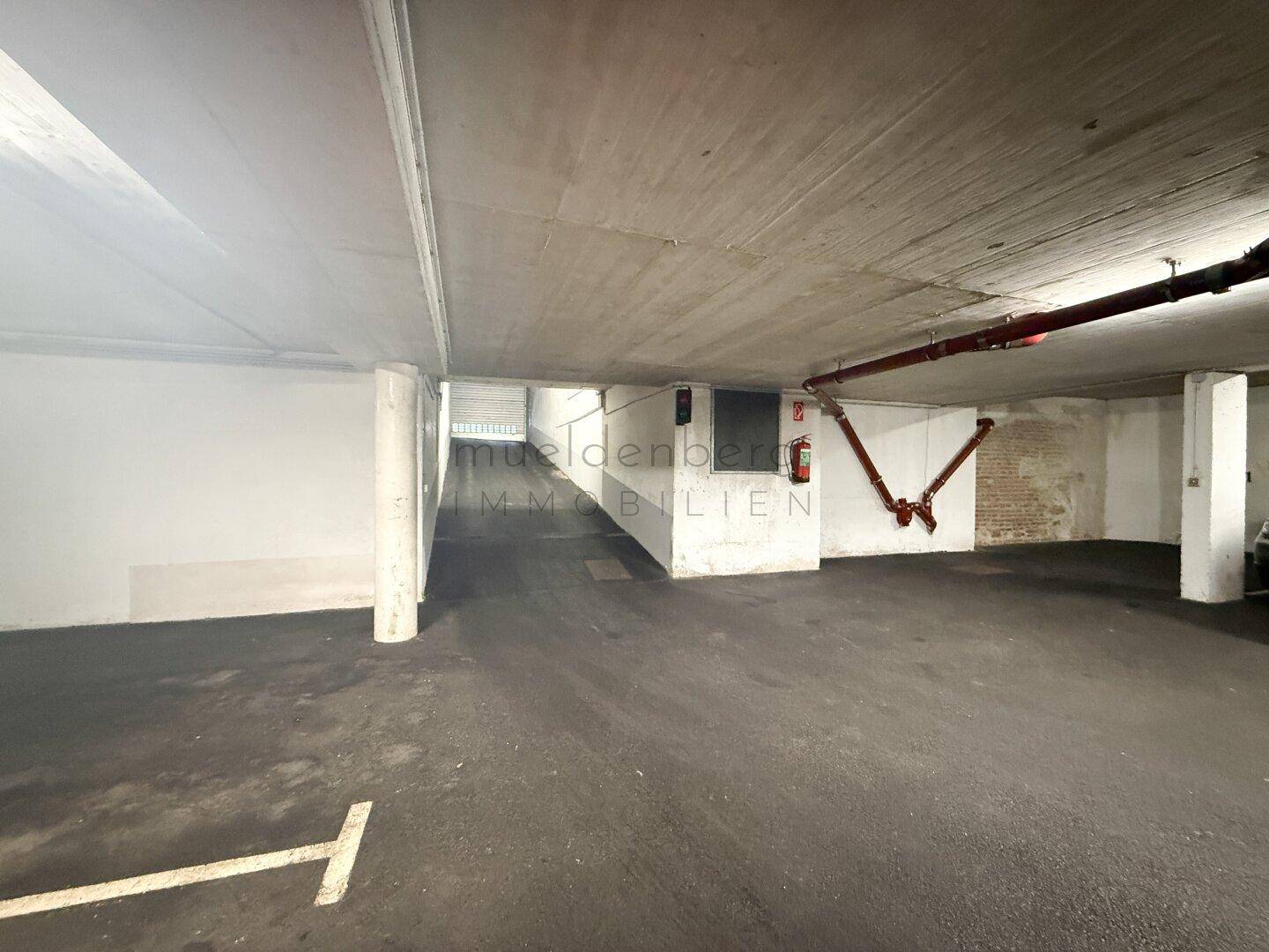 Geräumige Tiefgarage mit Betonboden und Brandschutzvorrichtungen.