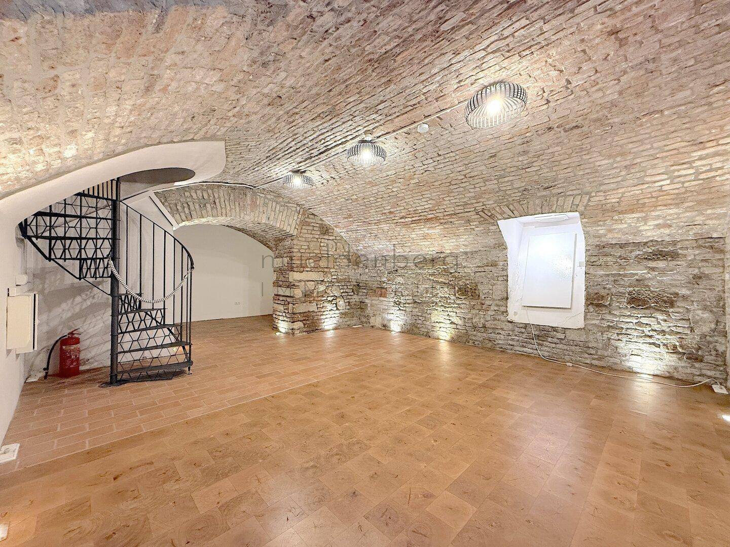 Geräumiger Raum mit Ziegelgewölbedecke, Terrakottafliesen und einer eleganten Wendeltreppe.