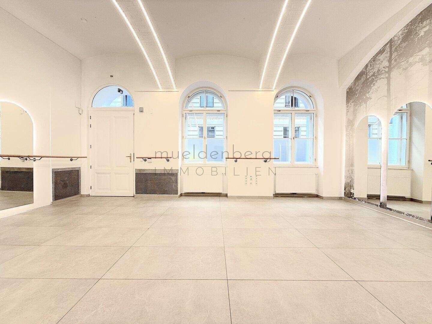 Großer, heller Raum mit hohen Gewölbedecken, großen Rundbogenfenstern und modernen Lichtleisten.