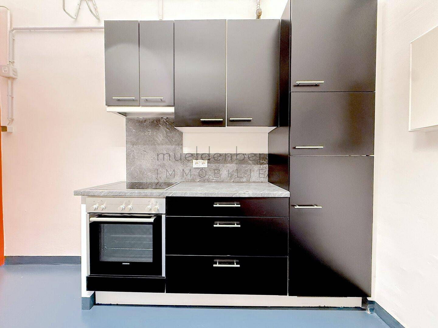 Moderne Küchenzeile mit schwarzen Schränken, Cerankochfeld und integriertem Backofen.