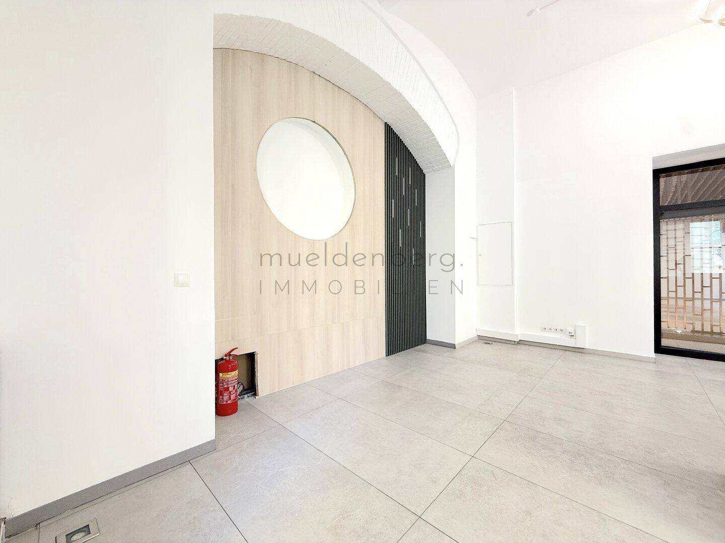 Moderner Innenraum mit Holzwandverkleidung, runder Aussparung und hellem Fliesenboden.