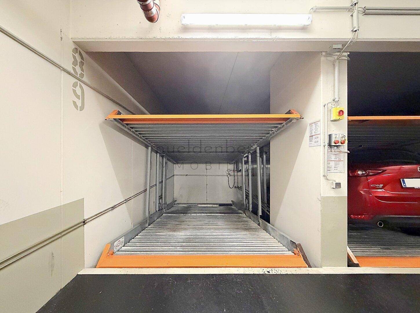 Leeres hydraulisches Parksystem in einer Tiefgarage, bereit für ein Fahrzeug.
