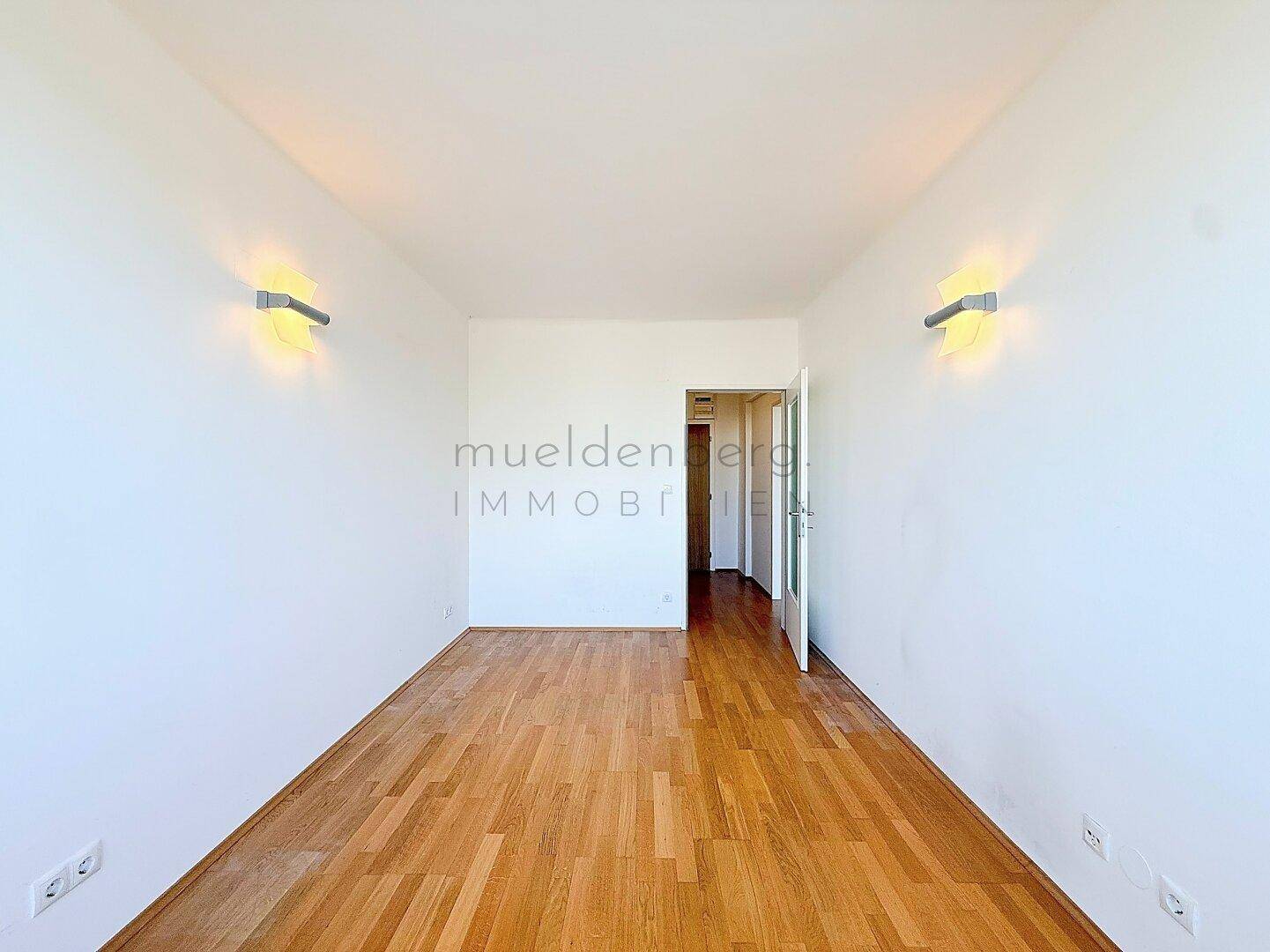 Geräumiges Zimmer mit Parkettboden und offenem Zugang zum Flurbereich.