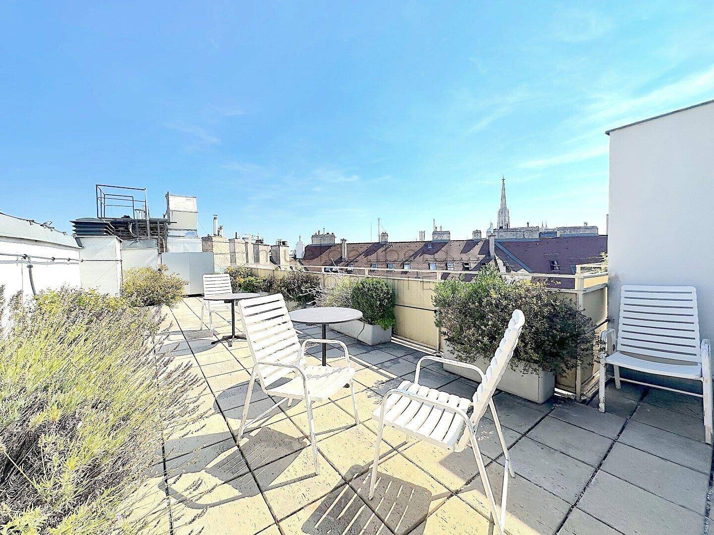 Helle Dachterrasse mit bequemen Lounge-Möbeln, Pflanzen und einem schönen Blick über die Stadt.