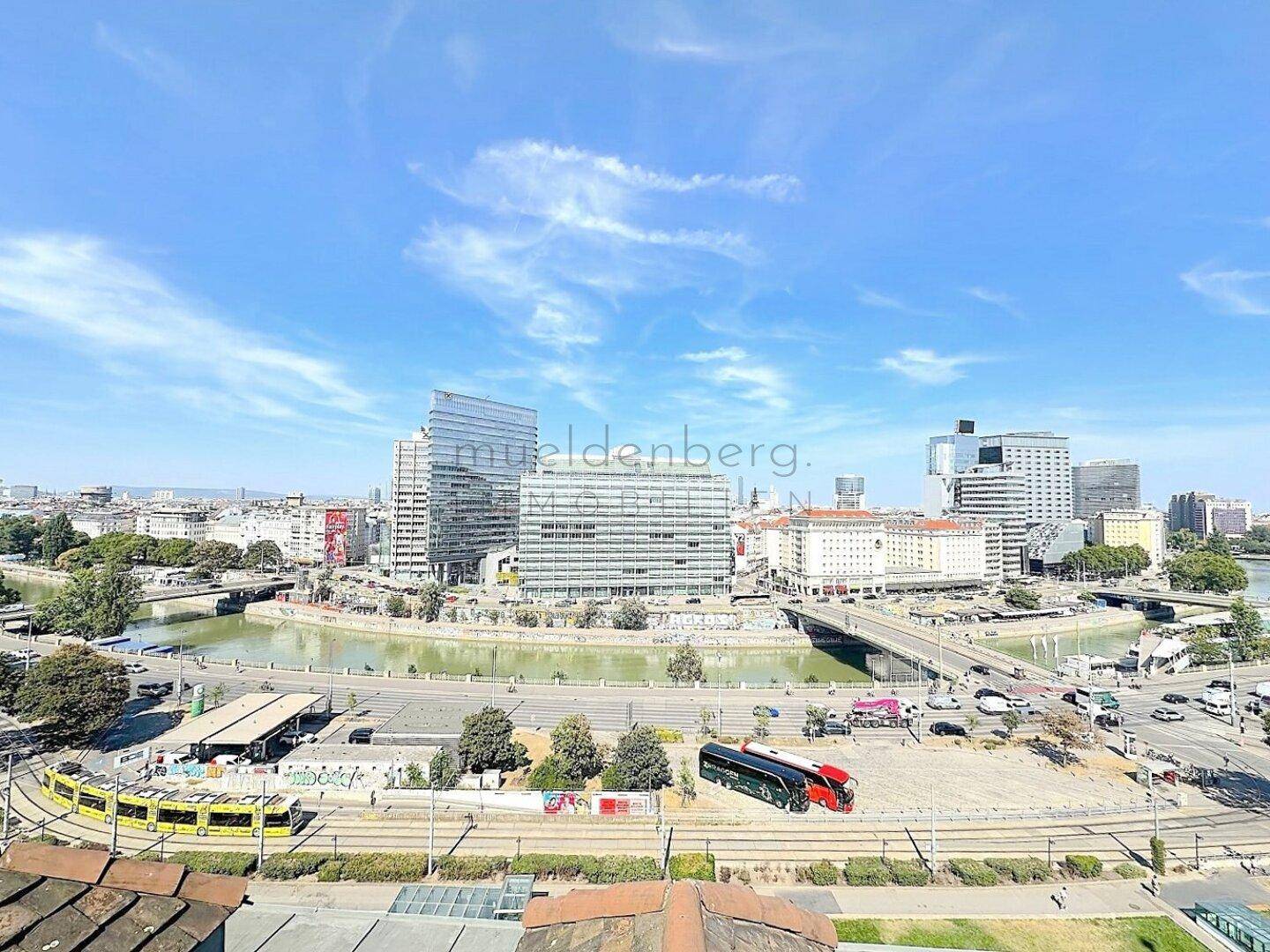 Panoramablick auf die Stadt mit Flusslandschaft, modernen Hochhäusern und belebten Verkehrswegen.