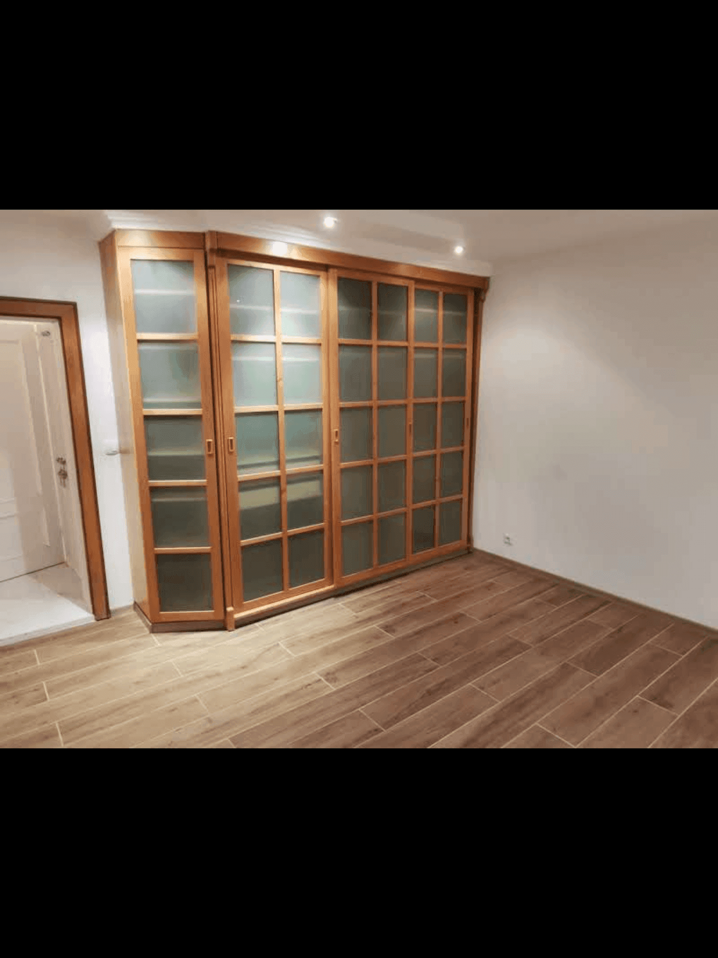Zimmer mit Holzoptik-Fliesenboden und integrierten Holzschränken.