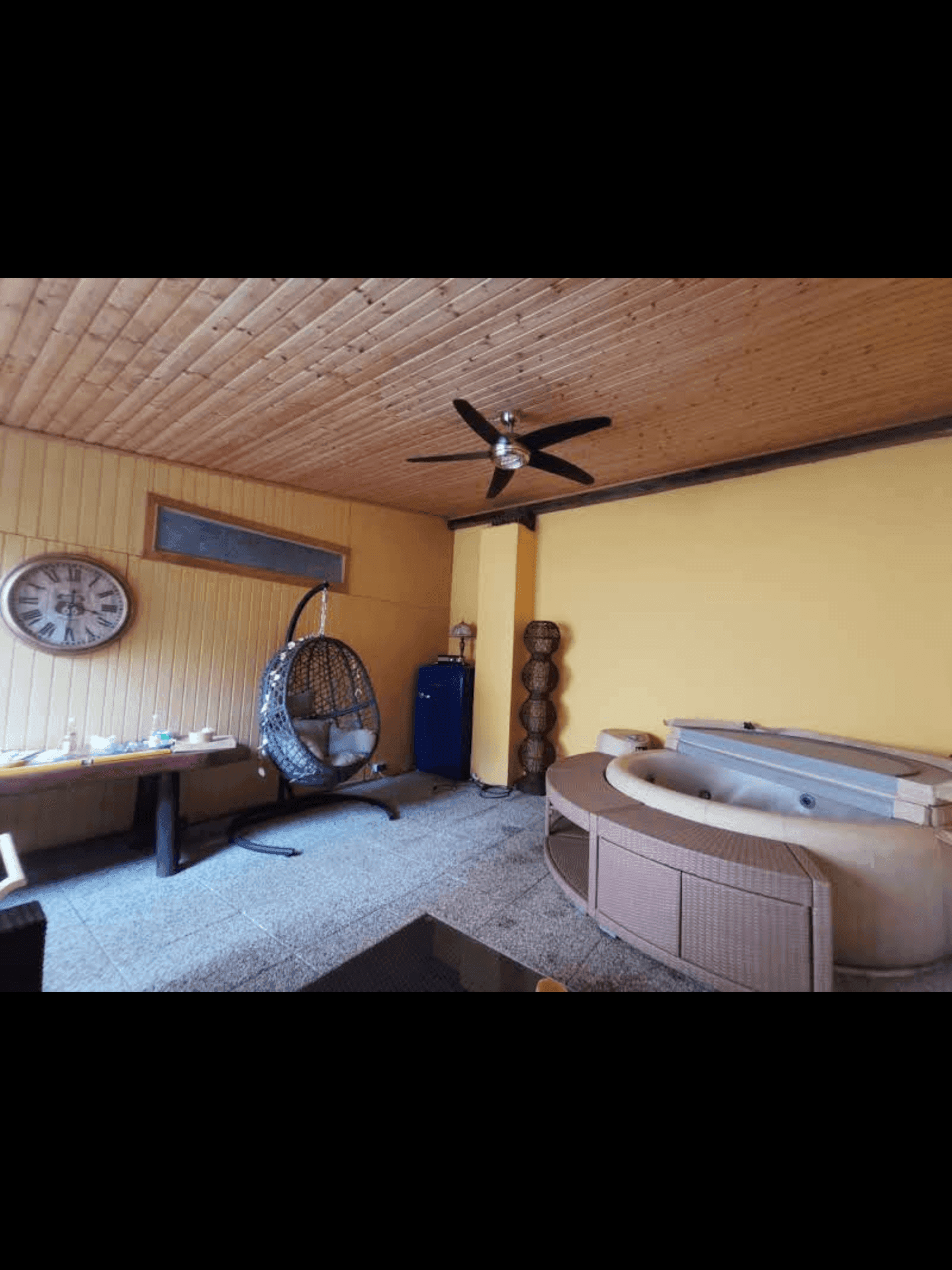 Entspannungsbereich mit Whirlpool, Holzdecke und gelben Wänden.