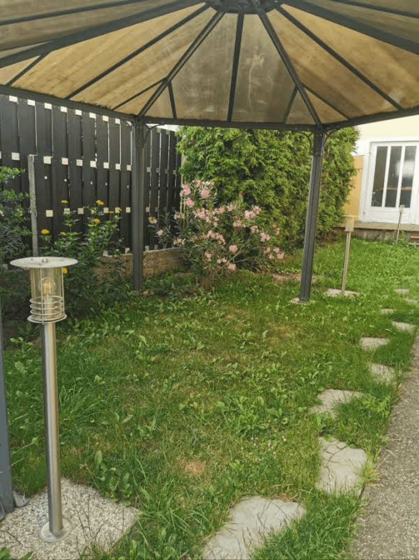Gartenbereich mit einem Pavillon, Rasenfläche und Trittsteinen.
