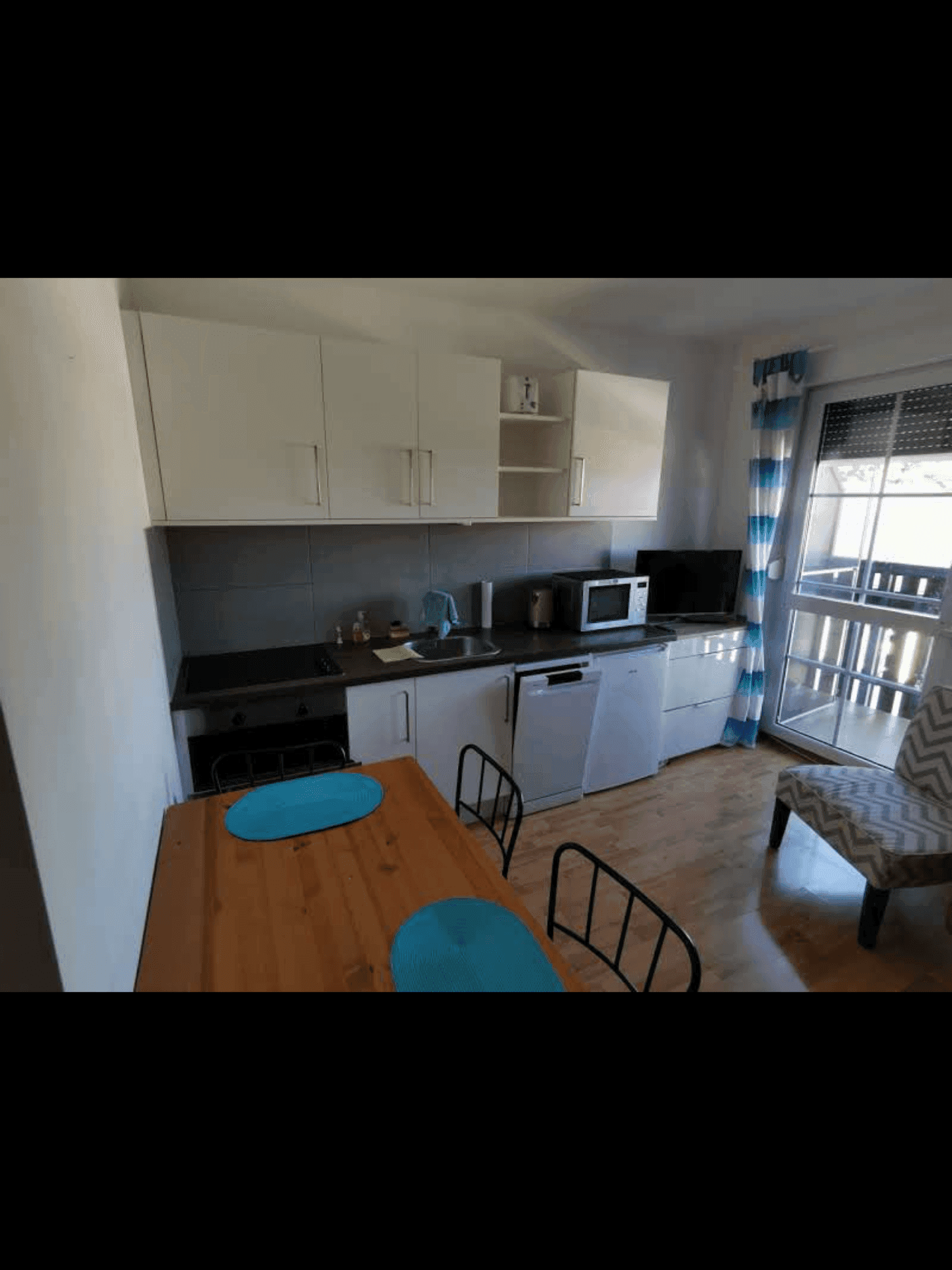 Kleine Küchenzeile mit Esstisch und direktem Zugang zu einem Balkon.