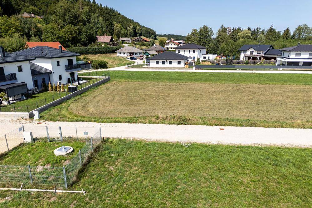 Weitläufige Ansicht einer ländlichen Wohnsiedlung mit Neubauten und großen Grünflächen.
