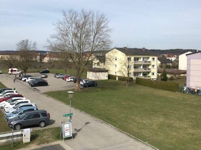 Außenansicht mit Parkplätzen, Grünflächen und umliegenden Wohngebäuden.