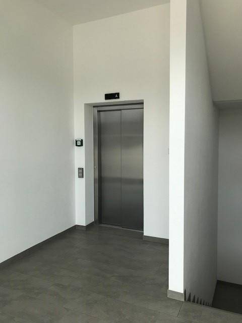 Moderner Aufzug in einem hellen Flur mit Fliesenboden.