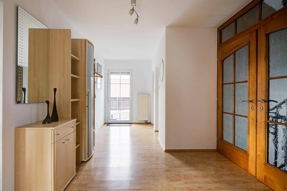 Geräumiger Flur mit Holzboden, Garderobe und viel Tageslicht durch die Eingangstür.