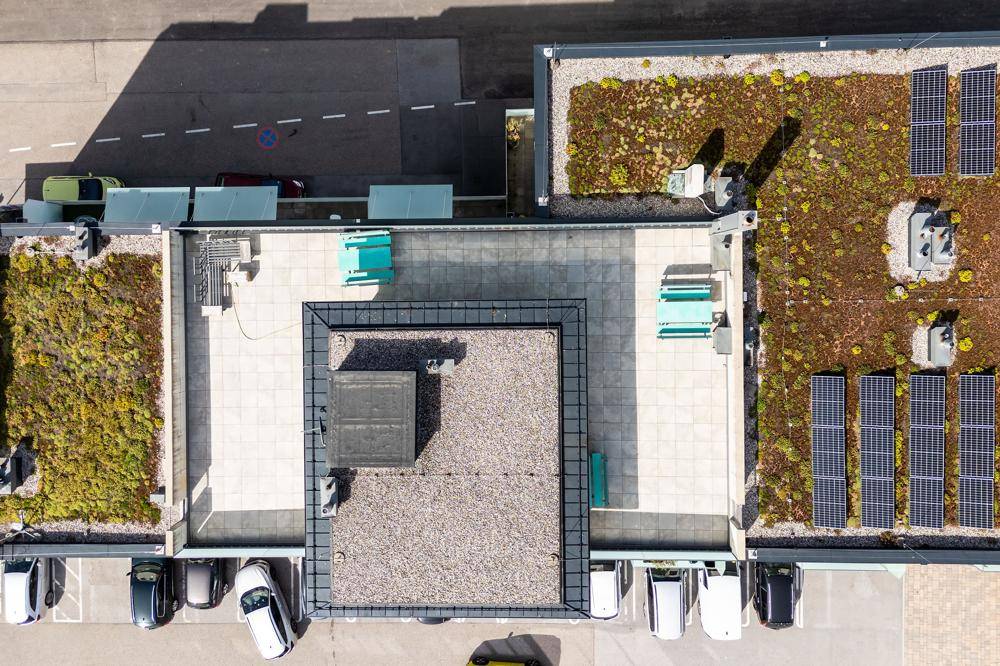 Draufsicht auf Gründächer mit Solaranlagen und Dachterrassen eines modernen Gebäudes.