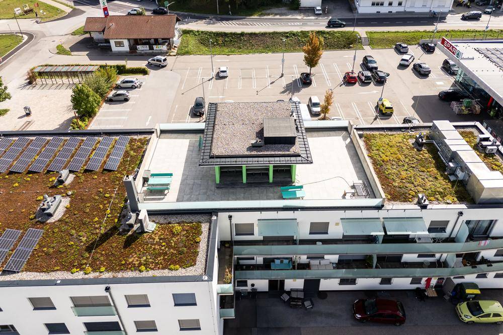 Luftaufnahme eines modernen Gebäudekomplexes mit Gründächern und Solaranlagen.