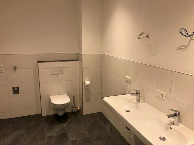 Helles Badezimmer mit wandhängendem WC und großem Doppelwaschbecken.