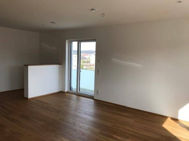 Heller Wohnbereich mit Holzboden und Zugang zu einem Balkon oder einer Terrasse.