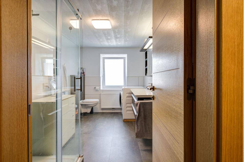 Modernes Badezimmer mit Dusche, Waschbecken, WC und Waschmaschine.
