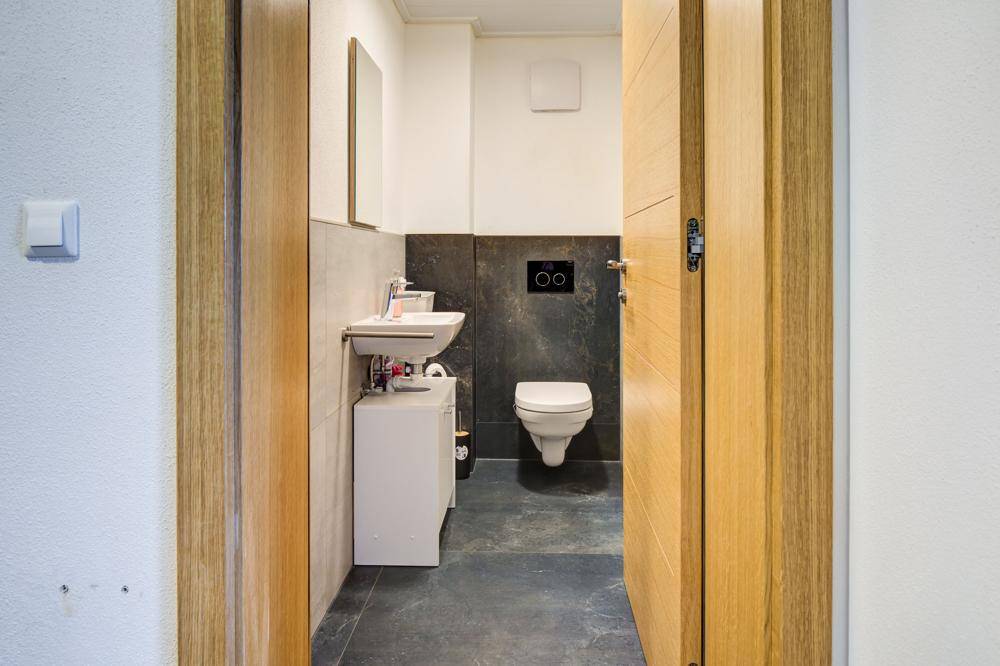 Modernes Gäste-WC mit wandhängendem WC und kleinem Waschbecken.