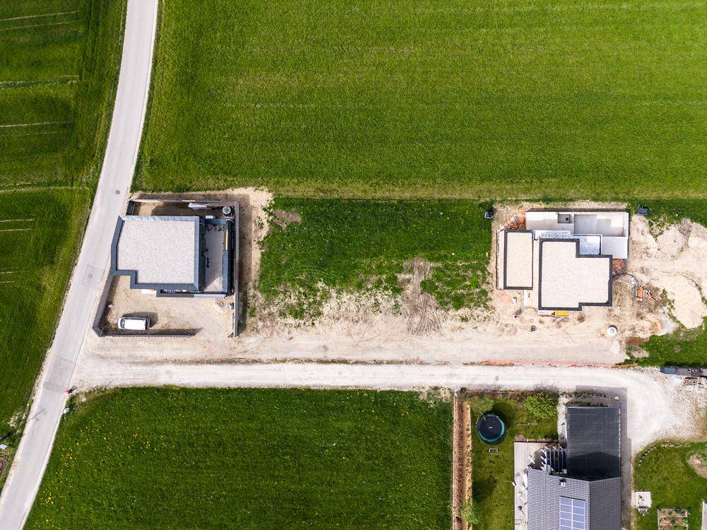 Draufsicht aus der Vogelperspektive auf zwei im Bau befindliche Häuser mit ihren Grundstücken.
