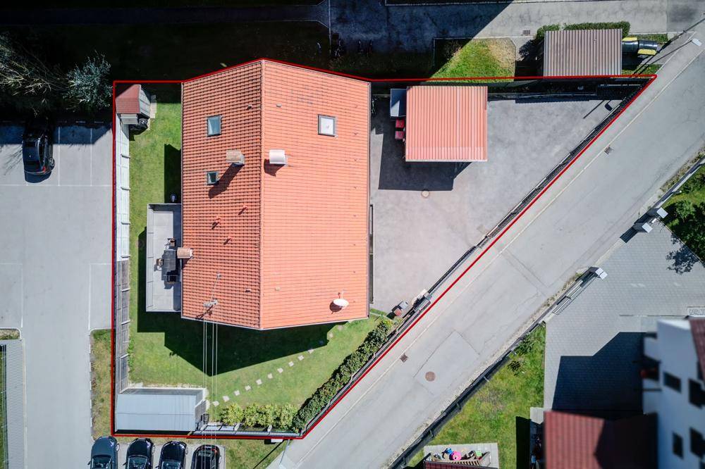 Draufsicht auf das Grundstück mit Einfamilienhaus, Carport und Gartenfläche, umrandet von einer roten Linie.