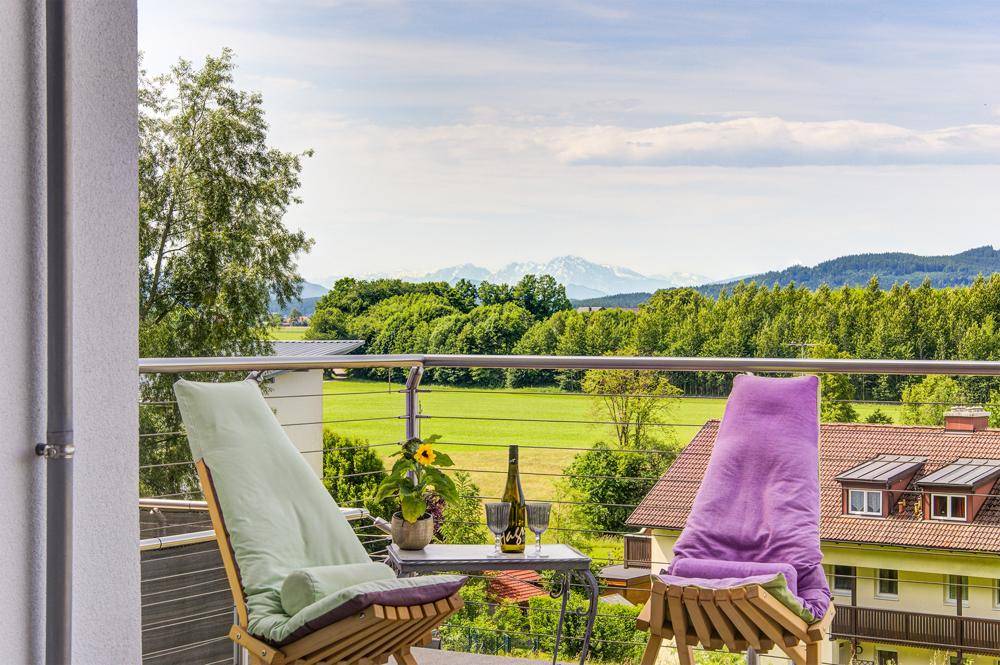 Gemütlicher Balkon mit Sitzgelegenheiten und weitem Blick auf die grüne Landschaft und Berge.