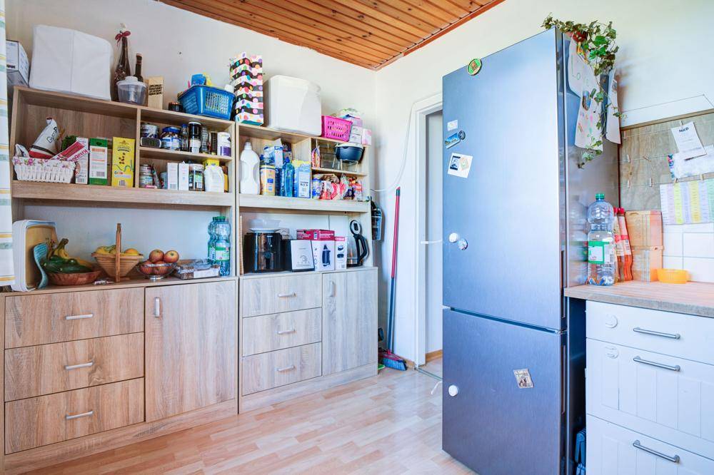 Küchenbereich mit viel Stauraum, Kühlschrank und Holzdecke.