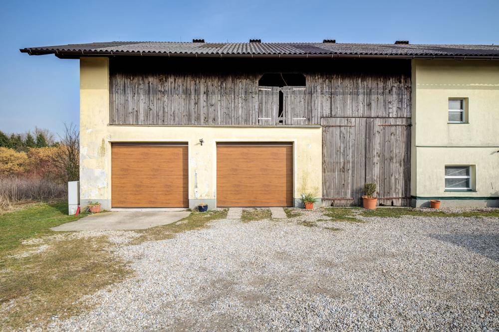 Rückseite des Landhauses mit zwei Garagentoren und Holzelementen unter dem Dach.
