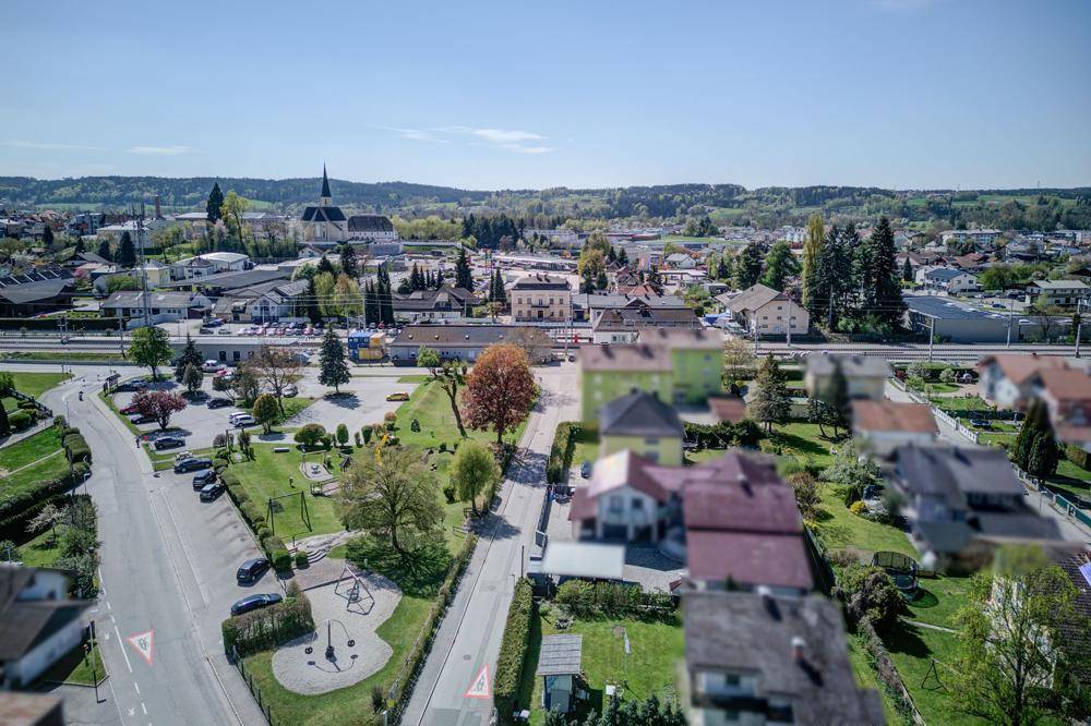 Panoramablick über eine Kleinstadt mit Kirche, Wohngebäuden und viel Grün.