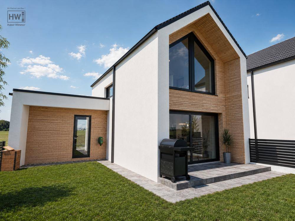 Hinterhof eines modernen Hauses mit kleiner Terrasse, Grill und Blick ins Grüne.