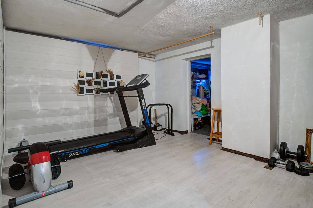 Fitnessraum im Keller mit Laufband und Hanteln.