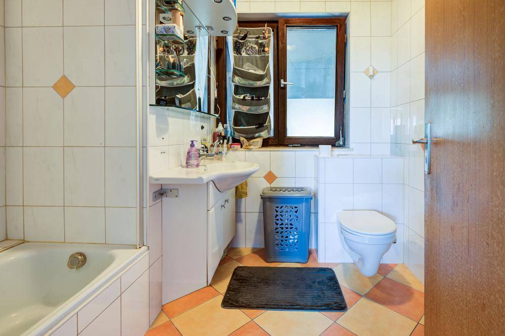 Badezimmer mit Badewanne, Waschbecken, WC und Fenster.