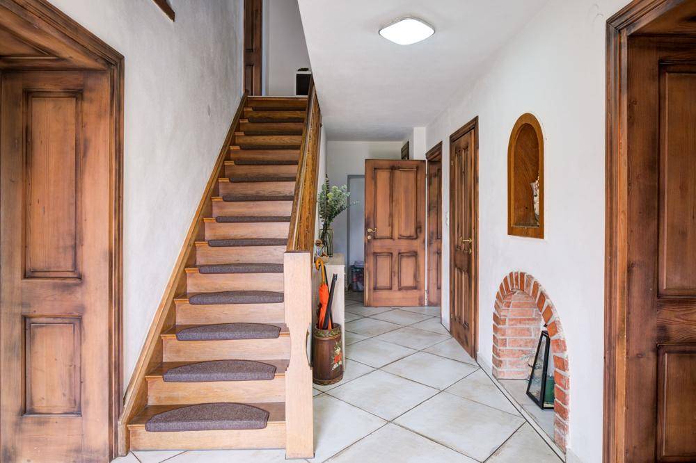 Heller Flur mit Holztreppe, Fliesenboden und rustikalen Holztüren.