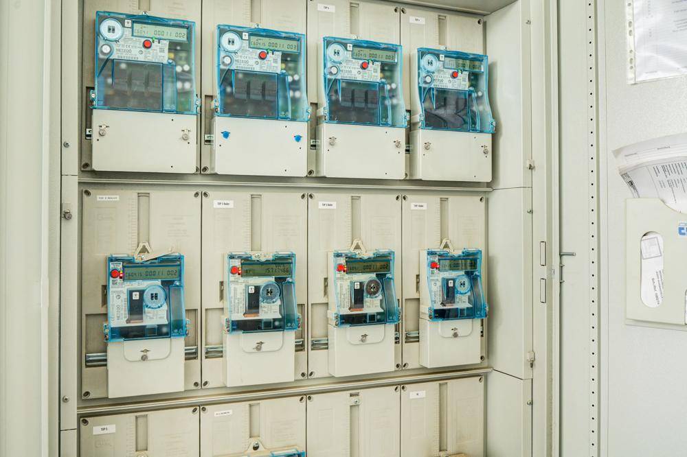 Reihe von modernen Stromzählern in einem Technikraum, die die Energieversorgung des Gebäudes überwachen.