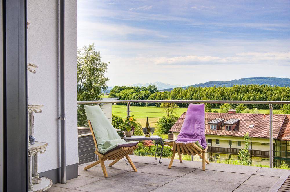 Gemütlicher Balkon mit Sitzgelegenheiten und weitem Blick auf die grüne Landschaft und Berge.