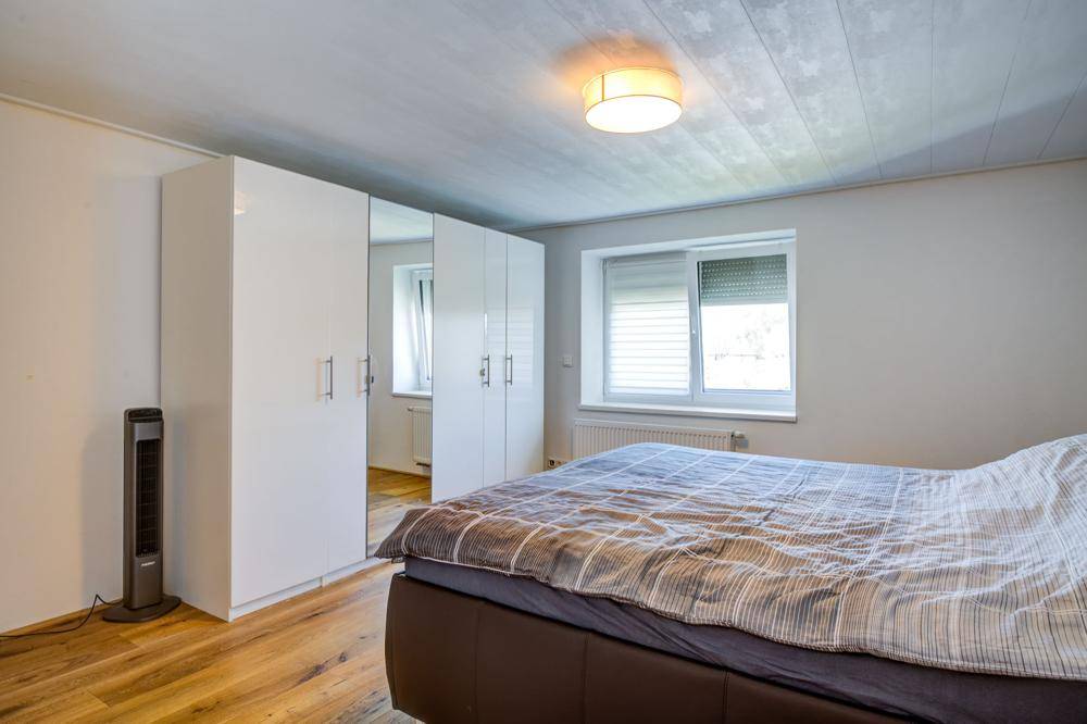 Schlafzimmer mit Doppelbett, weißen Kleiderschränken und Holzboden.