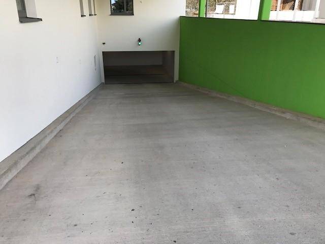 Zufahrt zur Tiefgarage mit Betonboden und grüner Wand.