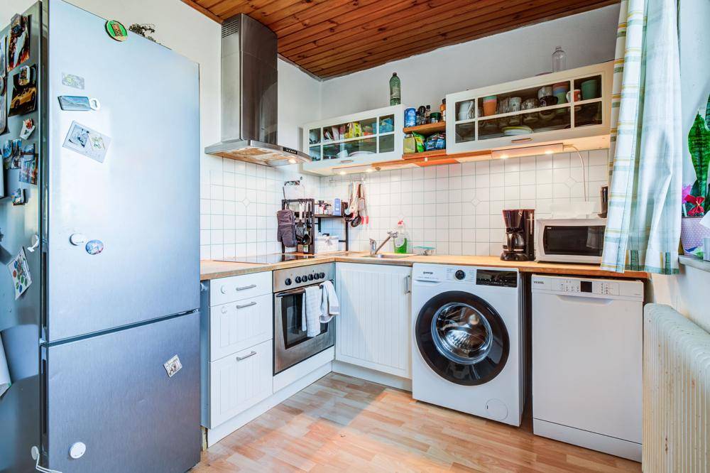 Funktionale Küche mit Holzbalkendecke, weißen Schränken und modernen Geräten.