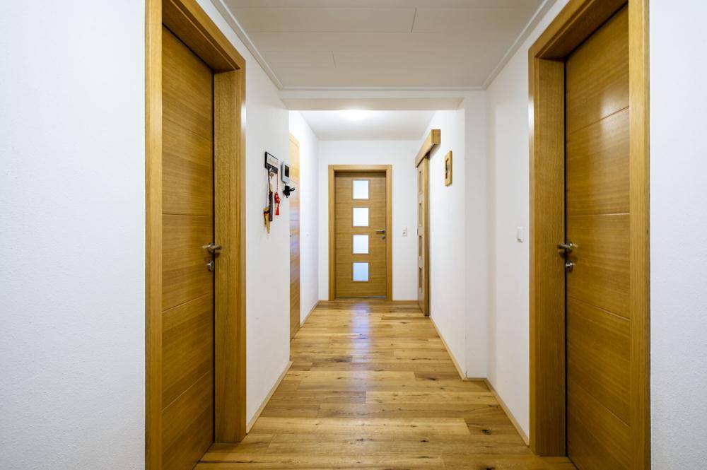 Heller Flur mit Holzboden und mehreren Holztüren, die zu den Zimmern führen.