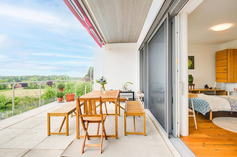 Helle Terrasse mit Essbereich und direktem Zugang zu einem Schlafzimmer mit Holzboden.