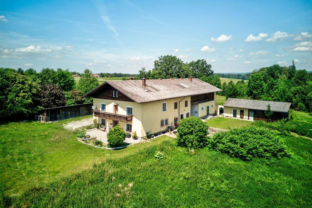 Weitläufiges Anwesen mit Haupthaus und Nebengebäude, umgeben von grüner Landschaft.