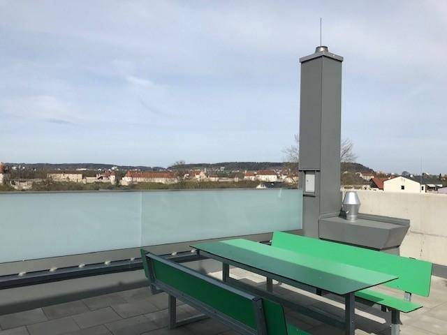 Geräumige Dachterrasse mit Sitzgelegenheiten und weitem Blick über die Stadt.