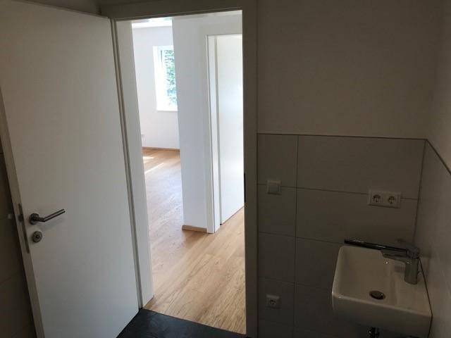 Kleines Gäste-WC mit Waschbecken und Blick in den angrenzenden Wohnbereich.