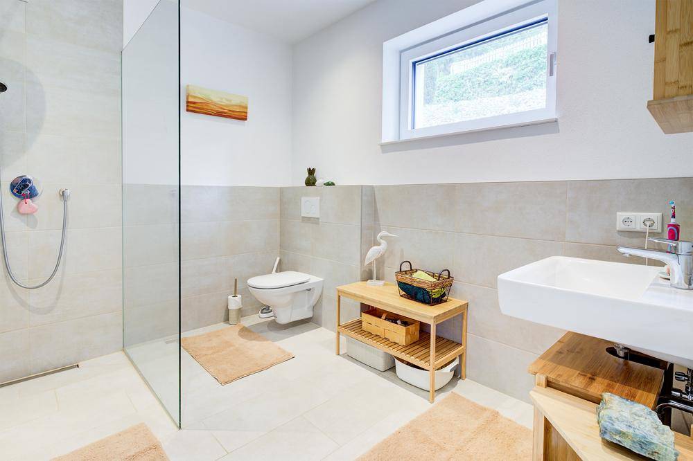 Helles Badezimmer mit begehbarer Dusche, modernem Waschbecken und Fenster.