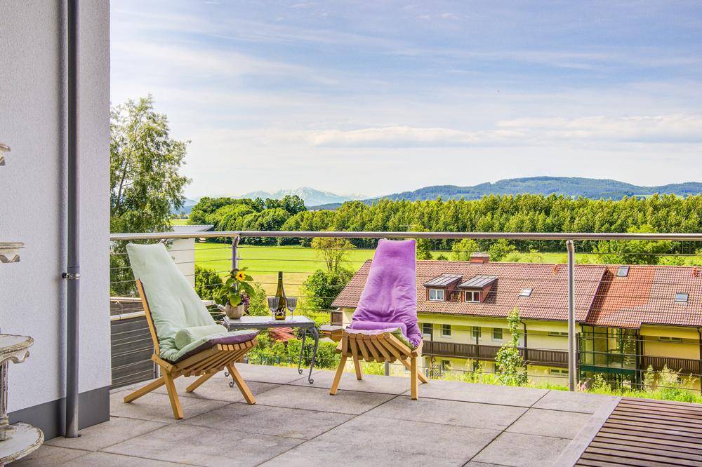 Geräumiger Balkon mit Fliesenboden, bequemen Stühlen und weitem Blick auf die Landschaft.