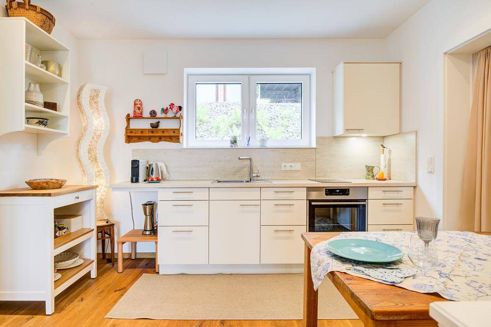 Moderne Einbauküche mit hellen Fronten, integriertem Backofen und Fenster.