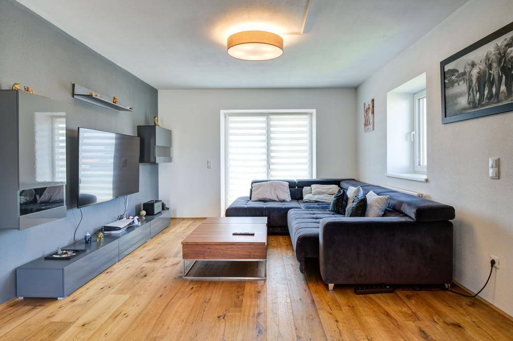 Gemütliches Wohnzimmer mit großem Ecksofa, Holzboden und modernem Entertainment-Bereich.