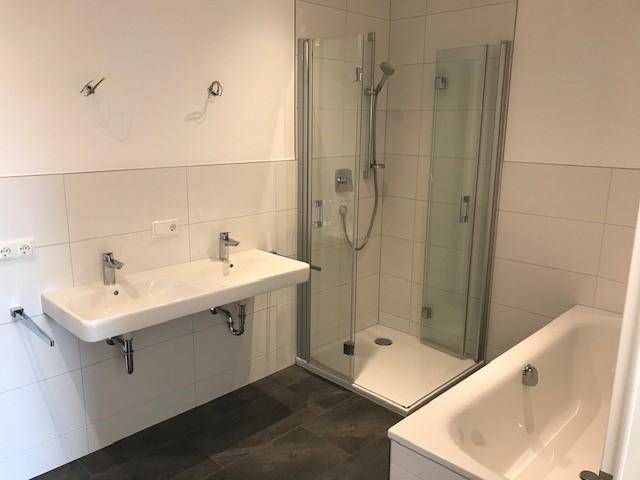 Modernes Badezimmer mit Doppelwaschbecken, Duschkabine und Badewanne.