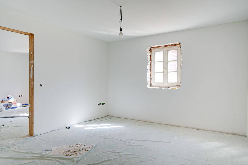 Leerer Raum im Rohbauzustand mit einem Fenster und vorbereiteten Elektroinstallationen.