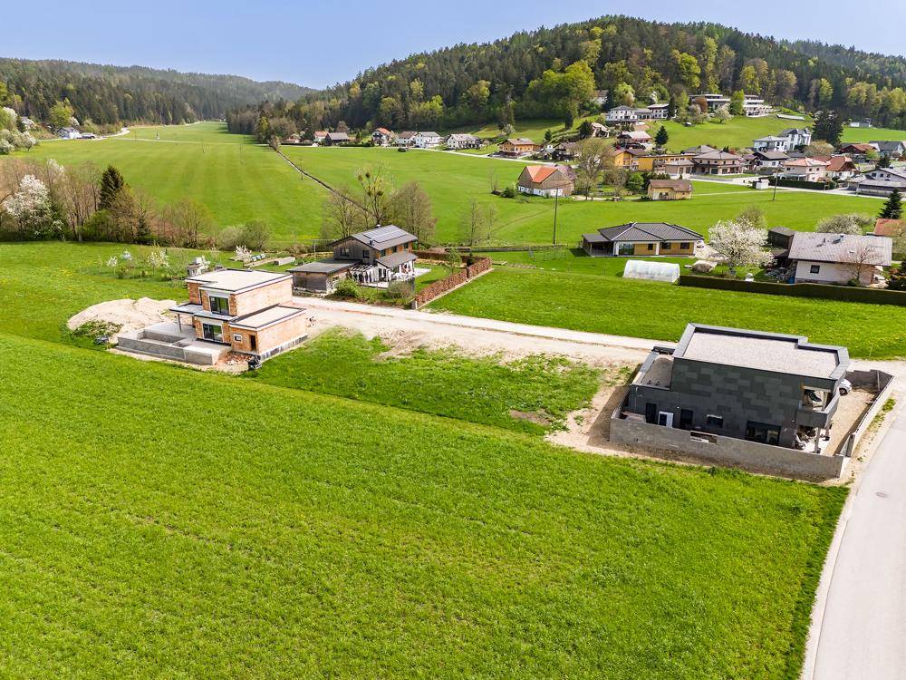Luftaufnahme von zwei modernen Neubauten in einer idyllischen ländlichen Umgebung mit viel Grün.